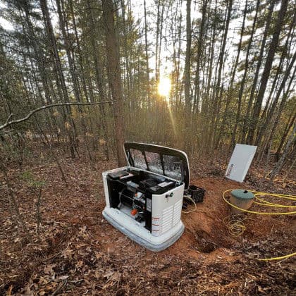 Generator installation in wooded area at sunrise, with surrounding trees and equipment.