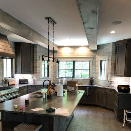 Modern kitchen with gray cabinets, spacious island, and natural light from large windows.