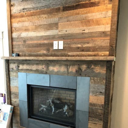 Modern rustic fireplace with a wooden mantel and natural wood wall accent.
