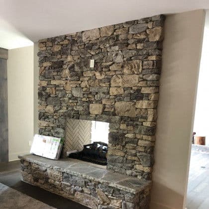 Modern stone fireplace with a sleek design and herringbone pattern backdrop.
