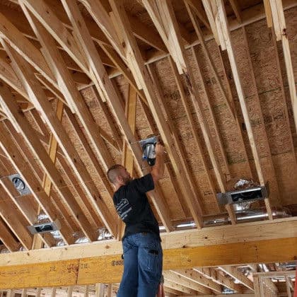 Construction worker installing beams in a house under construction, highlighting framing details.