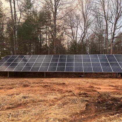 Solar panel installation in a wooded area, showcasing renewable energy technology.