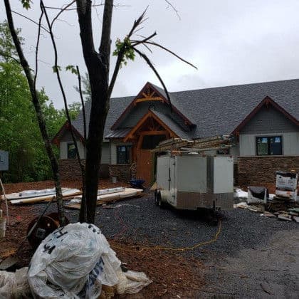 Newly constructed home with wooden accents, under renovation with equipment and debris visible.