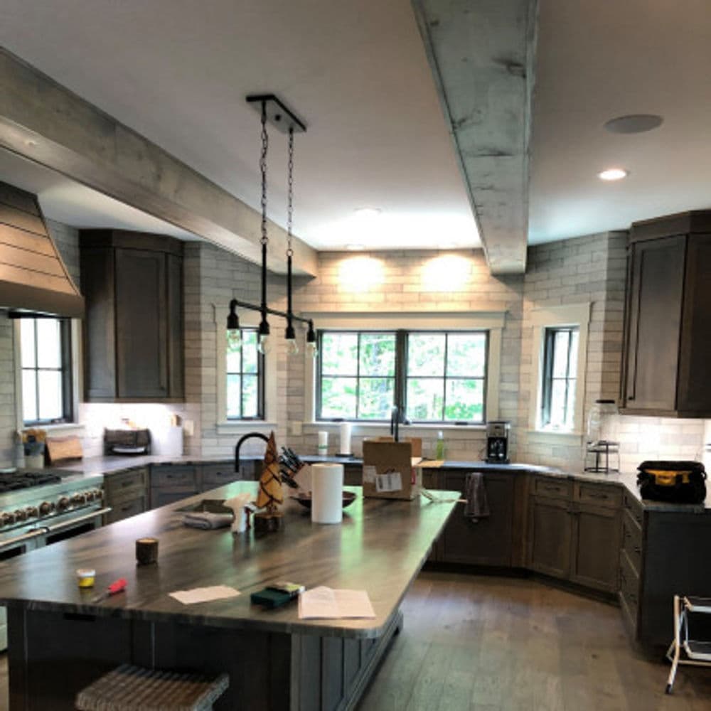 Modern kitchen with gray cabinetry, stainless steel appliances, and a large island. Natural light.
