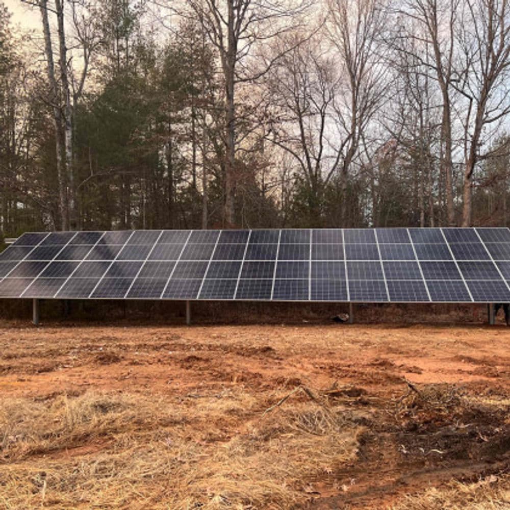 Solar panel array installed in a wooded area, showcasing renewable energy technology.